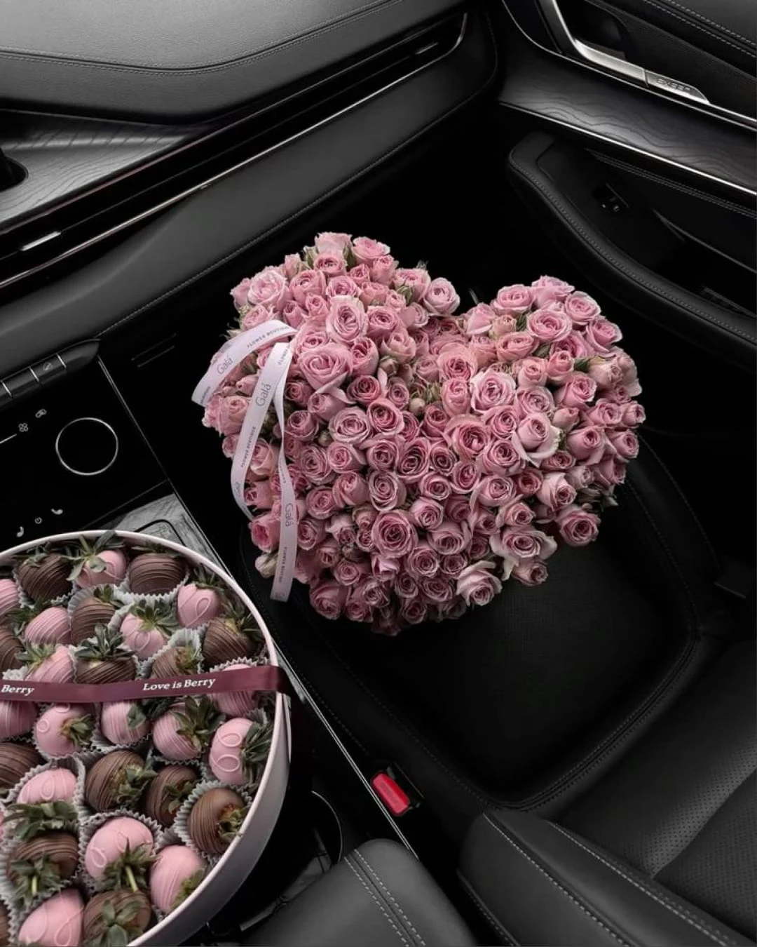 A heart of pink roses and chocolate strawberries in a car