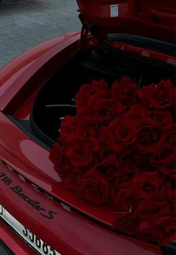 Red roses in the trunk of a red car